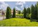 Beautifully manicured backyard featuring a lush lawn, privacy trees, and black metal fencing at 12505 Branford St, Carmel, IN 46032