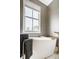 Relaxing bathroom featuring a freestanding tub, brass hardware, and stylish gray wallpaper at 12505 Branford St, Carmel, IN 46032