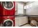 Laundry room with stacked red washer and dryer, sink, and storage cabinets at 12505 Branford St, Carmel, IN 46032