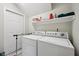 Functional laundry room equipped with a washer, dryer, a door, and a storage shelf at 15553 Portland Dr, Westfield, IN 46074