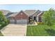Beautiful brick home features a three-car garage, manicured lawn, stone accents, and an inviting entrance at 19281 Scofield Ridge Blvd, Westfield, IN 46074