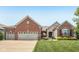 Charming brick home featuring a three car garage, manicured lawn and colorful landscaping in front at 19281 Scofield Ridge Blvd, Westfield, IN 46074
