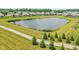 An aerial view of a community pond with a walking path and lush grassy surroundings in a residential area at 19281 Scofield Ridge Blvd, Westfield, IN 46074