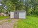 Metal shed with a roll up door and a hinged door provides storage and protection in a lush green yard at 3422 Hillside Ave, Indianapolis, IN 46218