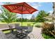 Outdoor patio features a dining set under a striped umbrella, surrounded by lush greenery and open green space at 392 Sandbrook Dr, Noblesville, IN 46062