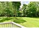 Private backyard, as seen from a wooden deck, with mature trees and a lush, landscaped lawn at 4115 Tansel Rd, Indianapolis, IN 46234
