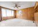Bright living room featuring neutral carpet, a ceiling fan, and large windows overlooking the surrounding greenery at 414 S Green St, Brownsburg, IN 46112
