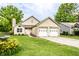 Charming home features a two-car garage, stone accents, and a well-manicured lawn with colorful flowers at 4380 Dunsany Ct, Indianapolis, IN 46254