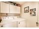 Well-lit laundry room featuring modern white washer and dryer, white storage cabinets, and decorative wall art at 4380 Dunsany Ct, Indianapolis, IN 46254