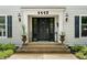 Elegant front entrance featuring a black door, stylish lanterns, decorative planters, and well-maintained landscaping at 4443 Mallard Pt, Columbus, IN 47201