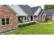 Inviting exterior featuring a brick home, covered porch with rocking chairs, lush lawn, and manicured landscaping at 4670 N 600 E, Franklin, IN 46131