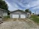 A detached two-car garage with white doors, accompanied by a small garden shed, offering ample storage at 4673 S 400 W, New Palestine, IN 46163