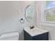 Bathroom featuring a modern vanity, oval mirror, toilet, and window with natural light at 5367 Penway St, Indianapolis, IN 46224