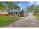 Charming gray home with a wooden porch, well-maintained lawn, and long driveway leading to a detached garage at 5367 Penway St, Indianapolis, IN 46224
