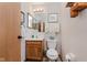 Compact bathroom featuring a vanity with a sink, a toilet, and a mirror with a decorative towel rack at 5515 Gateridge Ln, Indianapolis, IN 46237