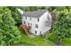 Aerial view of a house featuring a wooden deck with stairs, a lush lawn, and a black metal fence, surrounded by mature trees at 5857 Stone Pine Trl, Carmel, IN 46033