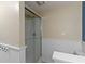 Modern bathroom featuring a shower with glass doors, wainscotting, and neutral walls, creating a clean and functional space at 5857 Stone Pine Trl, Carmel, IN 46033