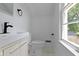 Contemporary bathroom features a modern sink, toilet, and natural light from the window at 6833 Evanston Ave, Indianapolis, IN 46220