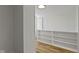 White hallway featuring hardwood floors, a built-in shelf, and natural light at 6833 Evanston Ave, Indianapolis, IN 46220