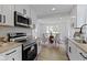 Modern kitchen featuring white cabinets, stainless steel appliances, and an adjacent dining area at 6833 Evanston Ave, Indianapolis, IN 46220