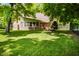 Lush backyard with mature trees, manicured lawn, privacy fence and a charming fire pit area at 7533 Deerfield Dr, Greenfield, IN 46140