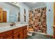 Well-lit bathroom featuring wood vanity, decorative shower curtain, and blue walls at 7533 Deerfield Dr, Greenfield, IN 46140