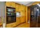 Kitchen featuring wood cabinets, black microwave and oven, with view of hardwood floor at 7533 Deerfield Dr, Greenfield, IN 46140