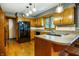 Bright kitchen with wooden cabinets, hardwood floors, black appliances, and eat-in counter at 7533 Deerfield Dr, Greenfield, IN 46140