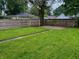 View of the flat backyard with a full wood fence, green grass, and brick paved patio area at 810 N Bosart Ave, Indianapolis, IN 46201