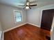 Cozy bedroom showcasing hardwood floors, a ceiling fan, one large window, and dark trim at 810 N Bosart Ave, Indianapolis, IN 46201