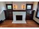 Living room fireplace featuring white brick, storage cabinets, sconces, and hardwood flooring at 810 N Bosart Ave, Indianapolis, IN 46201