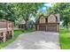 Exterior shot showcasing the well-maintained garages and property with a long driveway and mature trees at 838 Woodruff Place West Dr, Indianapolis, IN 46201