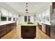 Sunlit kitchen with a large island featuring a cooktop, dark wood cabinets, and stainless steel appliances at 838 Woodruff Place West Dr, Indianapolis, IN 46201
