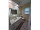 Bathroom featuring a vanity with illuminated mirror and a toilet next to a window at 8433 Fairwind Ct, Indianapolis, IN 46256