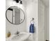 Bright bathroom with a round mirror, white vanity, and a blue hand towel at 8924 Stormhaven Ct, Indianapolis, IN 46256