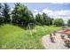 A well-maintained backyard with a swing set, trees, and a patio with furniture at 9215 Stones Bluff Pl, Indianapolis, IN 46113