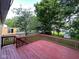 View of a back deck overlooking a grassy backyard with mature trees and a wooden privacy fence at 10316 Woodhaven Cir, Indianapolis, IN 46229