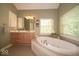 Elegant bathroom with a jacuzzi tub, double sink vanity, and large window at 10865 Fairwoods Dr, Fishers, IN 46037