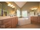 Elegant bathroom with a jacuzzi tub, double sink vanity, and large window at 10865 Fairwoods Dr, Fishers, IN 46037