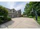 Rear exterior view featuring a large driveway leading to a two-car garage and basketball court at 10865 Fairwoods Dr, Fishers, IN 46037