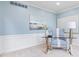 Bright home office with blue walls, a modern glass desk, stylish chair, and decorative wainscotting at 11266 Old Stone Dr, Indianapolis, IN 46236