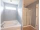Bright bathroom offers a soaking tub, a glass shower, and wood-look flooring at 13829 Black Canyon Ct, Fishers, IN 46038