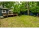 The backyard shows lush green grass, a wooden deck, large shade trees and a tall blue wooden fence at 1515 Randall Rd, Indianapolis, IN 46240