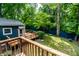 Backyard featuring a wooden deck and a blue privacy fence surrounded by mature trees and lush greenery at 1515 Randall Rd, Indianapolis, IN 46240