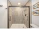 Modern bathroom featuring a glass enclosed shower with gray tiling and minimalist fixtures at 1605 Westlane Rd, Indianapolis, IN 46260