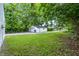 View of the detached garage with green trees and gravel driveway in the backyard at 1933 Tallman Ave, Indianapolis, IN 46218