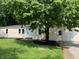 View of the home's entrance and multiple windows surrounded by lush greenery and a well-kept lawn at 221 N 9Th St, Elwood, IN 46036