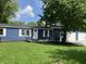 Blue home featuring white trim, lush lawn, and mature trees, with a convenient two-car garage at 221 N 9Th St, Elwood, IN 46036