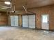 Three car garage with concrete floor, plywood walls, and three white garage doors at 221 N 9Th St, Elwood, IN 46036