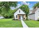 Charming bungalow featuring a walkway to the porch, lush green lawn, and updated black trim at 3035 Guilford Ave, Indianapolis, IN 46205